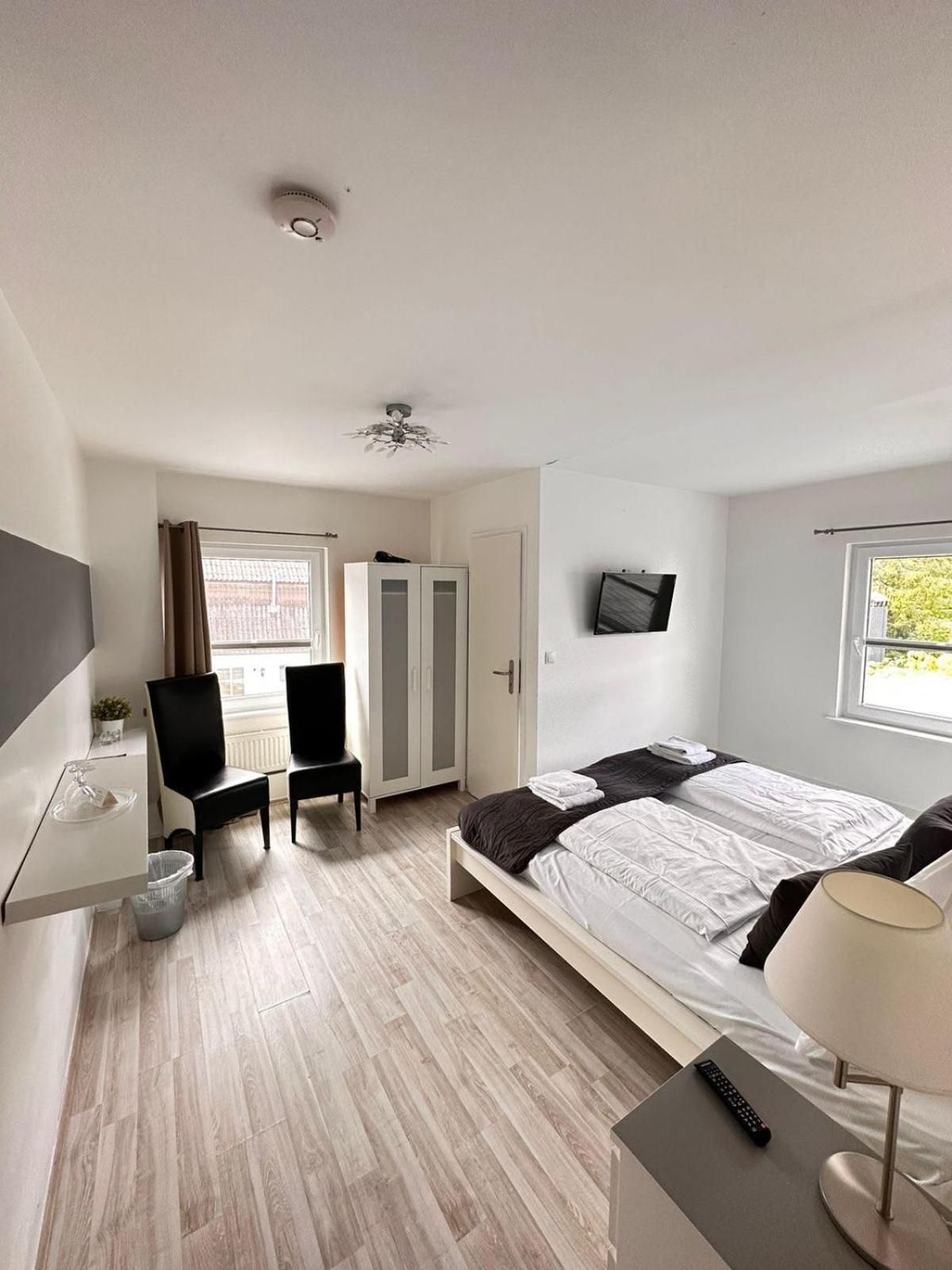 Ein Schlafzimmer mit einem Bett, einem Schreibtisch, einem Stuhl, einem Fernseher und einem Fenster.