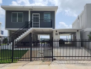A two-story house with a covered patio, a staircase, and a fenced yard. - A Home away from home (Fajardo)