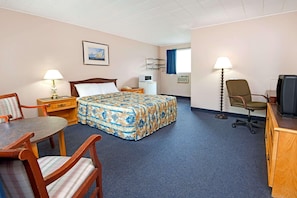 Een hotelkamer met een bed, een bureau, een stoel, een televisie en een lamp.