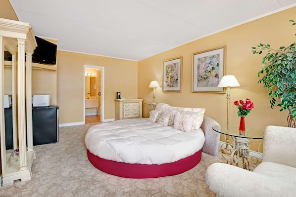 Een hotelkamer met een groot bed, een bureau, een stoel, een plant en kunstwerken aan de muren.