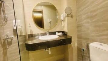 Een moderne badkamer met een glazen douchecabine, een ronde spiegel, een zwart aanrecht en een wit toilet.