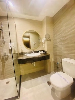 Ein modernes Badezimmer mit Duschkabine aus Glas, einem runden Spiegel, einer schwarzen Ablage und einer weißen Toilette.