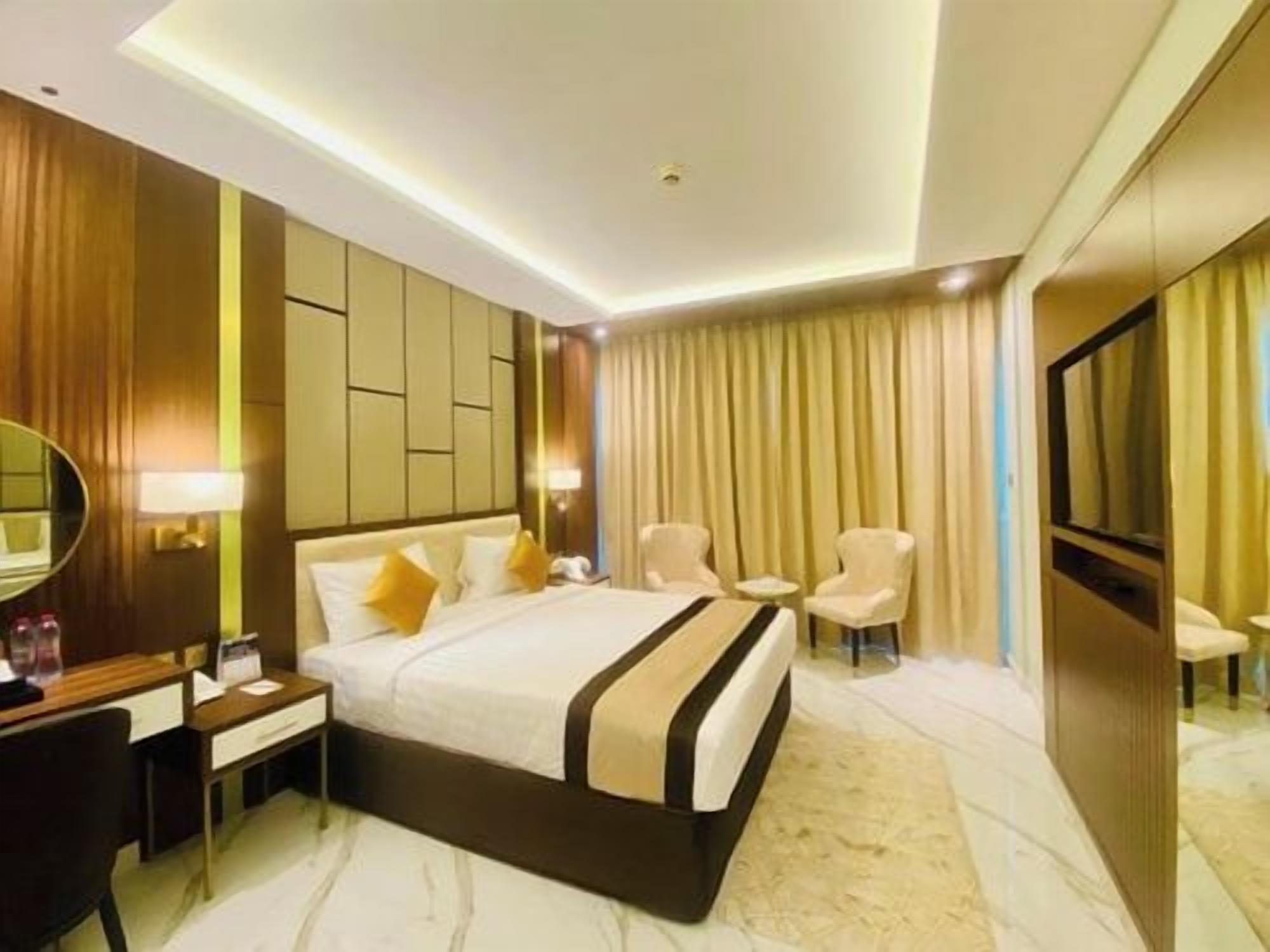 Une chambre d’hôtel avec un grand lit, des tables de chevet, un bureau et une chaise.
