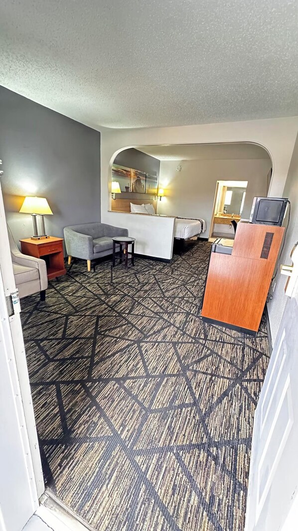 Une chambre d’hôtel avec un lit, un bureau, une chaise, une lampe et un miroir.