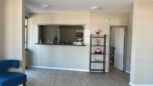 Et receptionområde med disk, en blå stol og en reol med pynt.