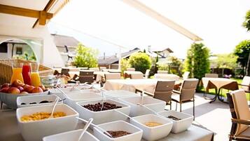 Un ricco buffet per la colazione all'aperto, con diverse pietanze e postazioni per sedersi.