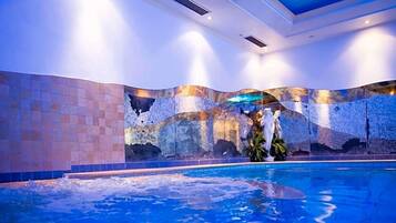 Una piscina interna con parete piastrellata e soffitto con illuminazione a incasso.