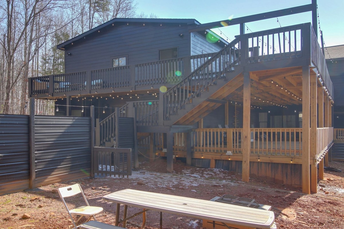 A two-story wooden house with a balcony and deck, surrounded by a fence.
