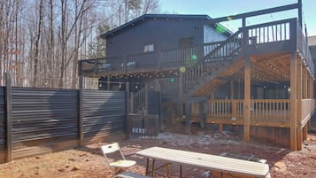 A two-story wooden house with a balcony and deck, surrounded by a fence.