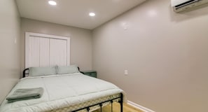 A bedroom with a bed, a nightstand, a window with blinds, and an air conditioning unit. - Peaceful Countryside Boutique Hotel  (Commerce)