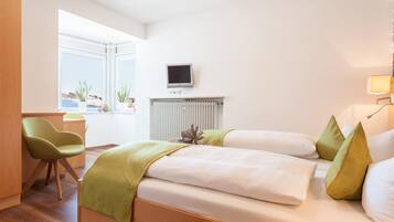 Ein Hotelzimmer mit Bett, Schreibtisch, Stuhl, Fernseher und einem Fenster mit Blick.