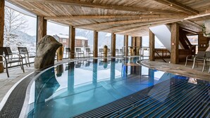Una piscina interior moderna con techo de madera y ventanas amplias.