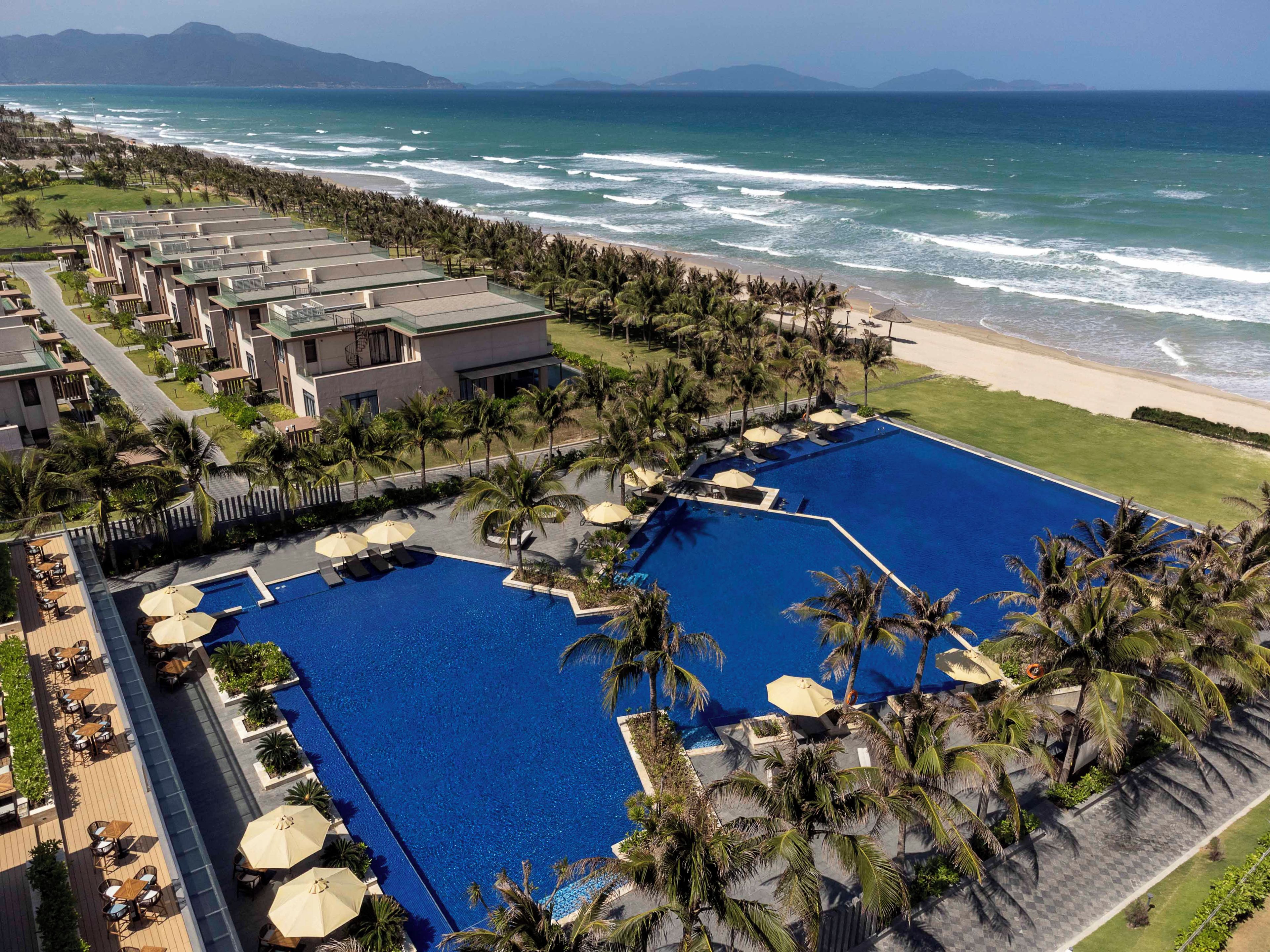 Un resort con una gran piscina, acceso a la playa y varias edificaciones.