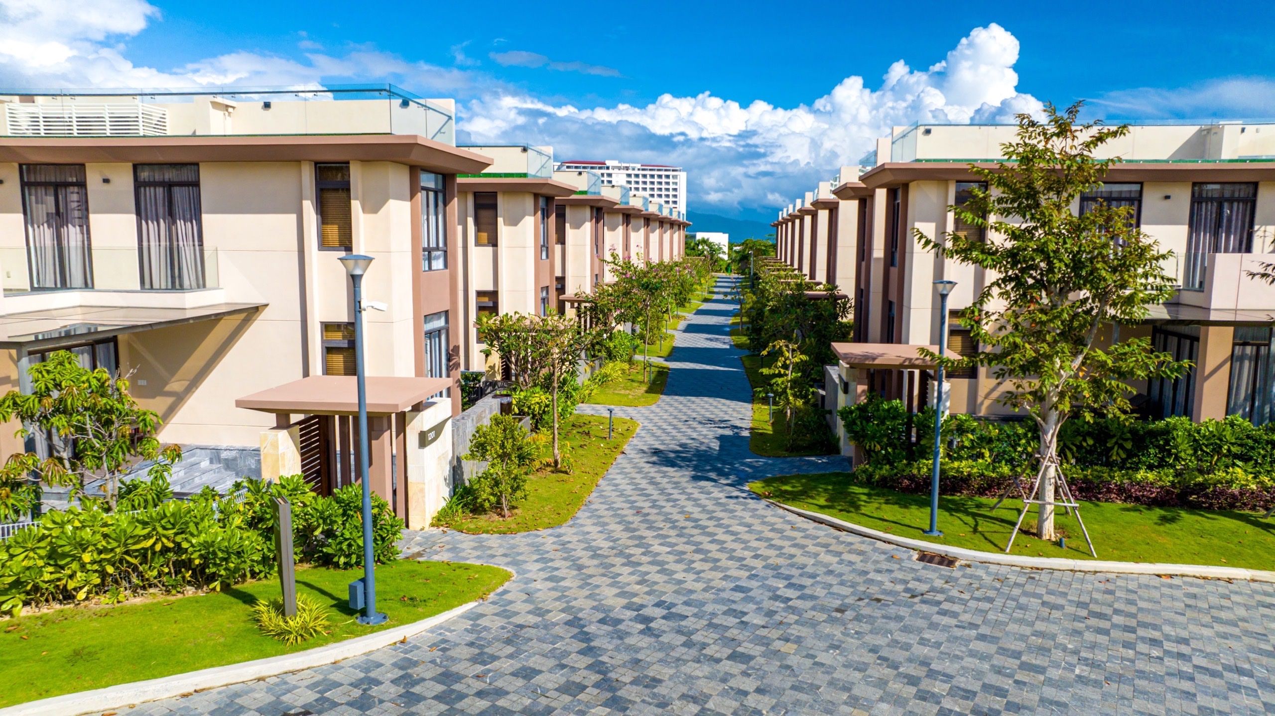 Un barrio residencial con modernos edificios de apartamentos, un sendero pavimentado y abundante vegetación cuidada.