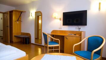 A hotel room with a bed, a desk, two chairs, a television, and a mirror.