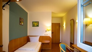 Een hotelkamer met een bed, een stoel, een bureau, een spiegel en een deur.