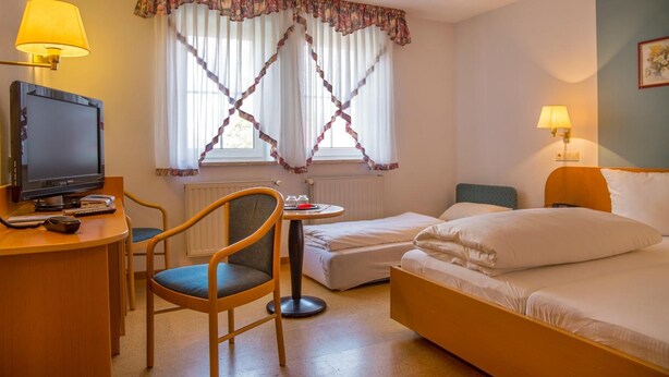 Een hotelkamer met een bureau, een televisie, een stoel, een bed en twee bedlampen.