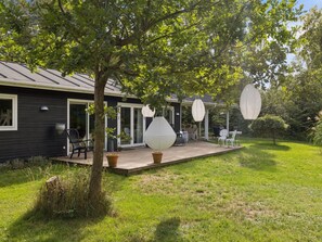 Ein Haus mit überdachter Terrasse, Sitzgelegenheiten im Freien und großen, dekorativen Papierlampen.