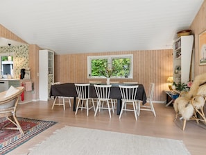 A dining area with a table and chairs, a window with a view of greenery, and a kitchen area with cabinets and a coffee machine. - "Ølvir" - 525m from the sea by Interhome (Nykøbing Sj)