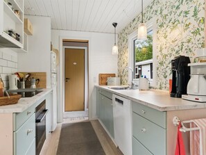 A compact kitchen with a wooden door, white cabinets, a coffee maker, and a sink. - "Ølvir" - 525m from the sea by Interhome (Nykøbing Sj)