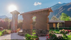 A traditional stone structure with a tiled roof, surrounded by a garden with various flowering plants.