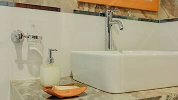 Un baño con una bañera blanca, un dispensador de jabón de vidrio y una botella de jabón sobre una encimera de mármol.