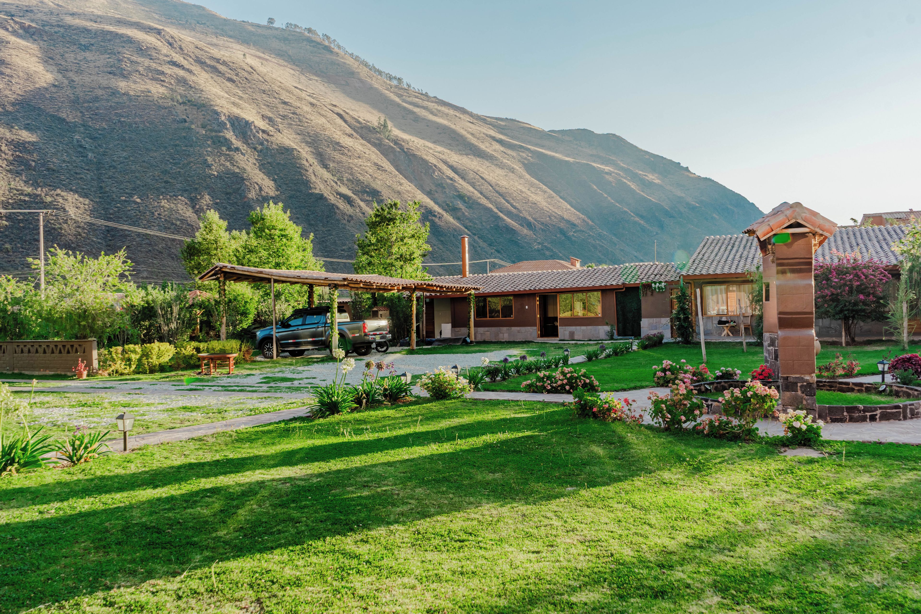 Une maison dotée d’un patio, entourée d’un jardin bien entretenu et avec une chaîne de montagnes en toile de fond.