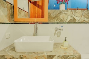 A bathroom with a rectangular sink, a mirror, a potted plant, and a soap dispenser. - CCAYPA Willka Qhichwa (Calca)