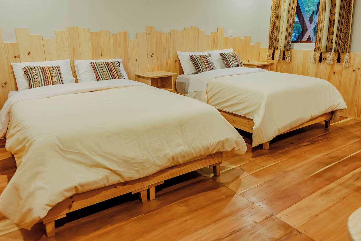 A hotel room with two wooden beds, white bedding, and a wooden floor.