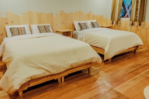A hotel room with two wooden beds, white bedding, and a wooden floor. - CCAYPA Willka Qhichwa (Calca)