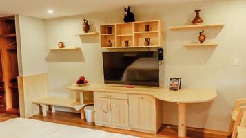 A room with a bed, a TV, wooden shelves with decorative items, and a bench.