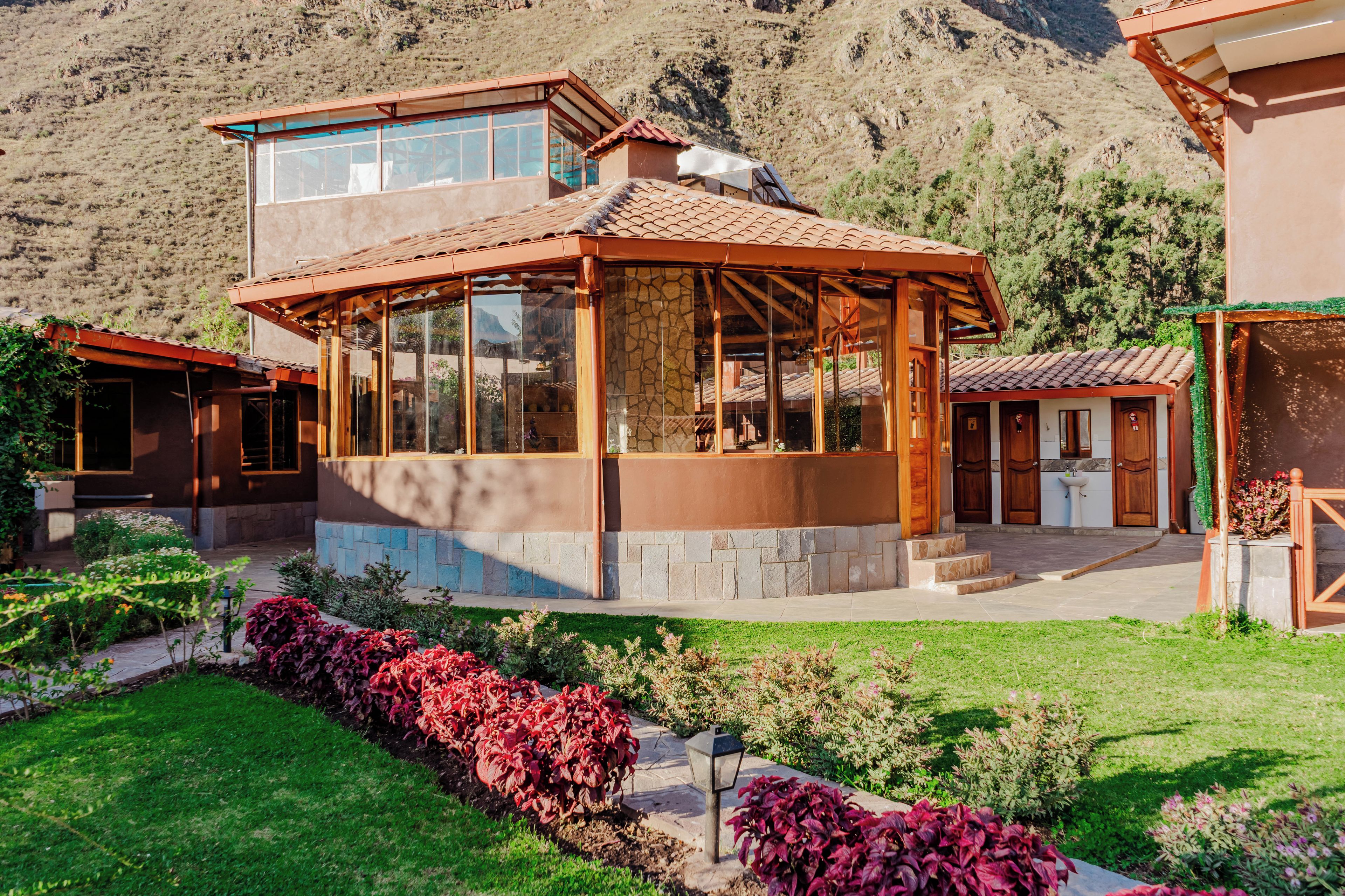 A two-story house with a glass-enclosed patio and a mountain backdrop.