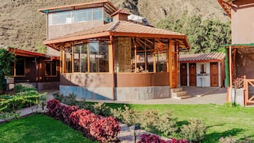 A two-story house with a glass-enclosed patio and a mountain backdrop.