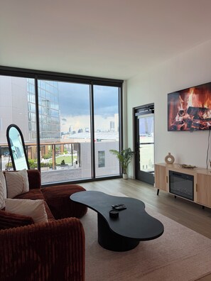 A modern living room with a large window, a flat-screen TV, a fireplace, and a sofa. - Cozy 1-bedroom apartment in charming Atlanta with AC and gym access (Atlanta)