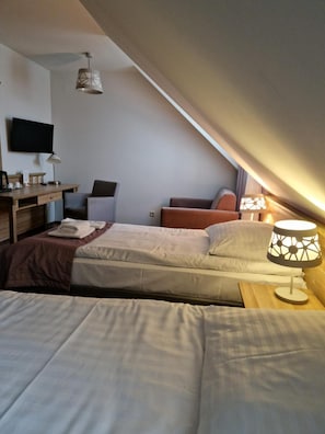 A bedroom with two beds, a desk, a chair, and a TV mounted on the wall. - Pod Szyszkami (Krotoszyn)
