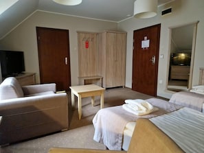 A hotel room with a sofa, a bed, a small table, and a television. - Pod Szyszkami (Krotoszyn)