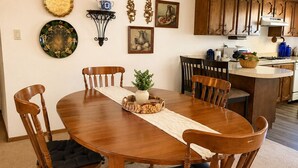 A dining area with a wooden table and chairs, a small potted plant, and wall decorations. - Vintage Charm-Modern Comfort•2BR/2BA home (Lovington)