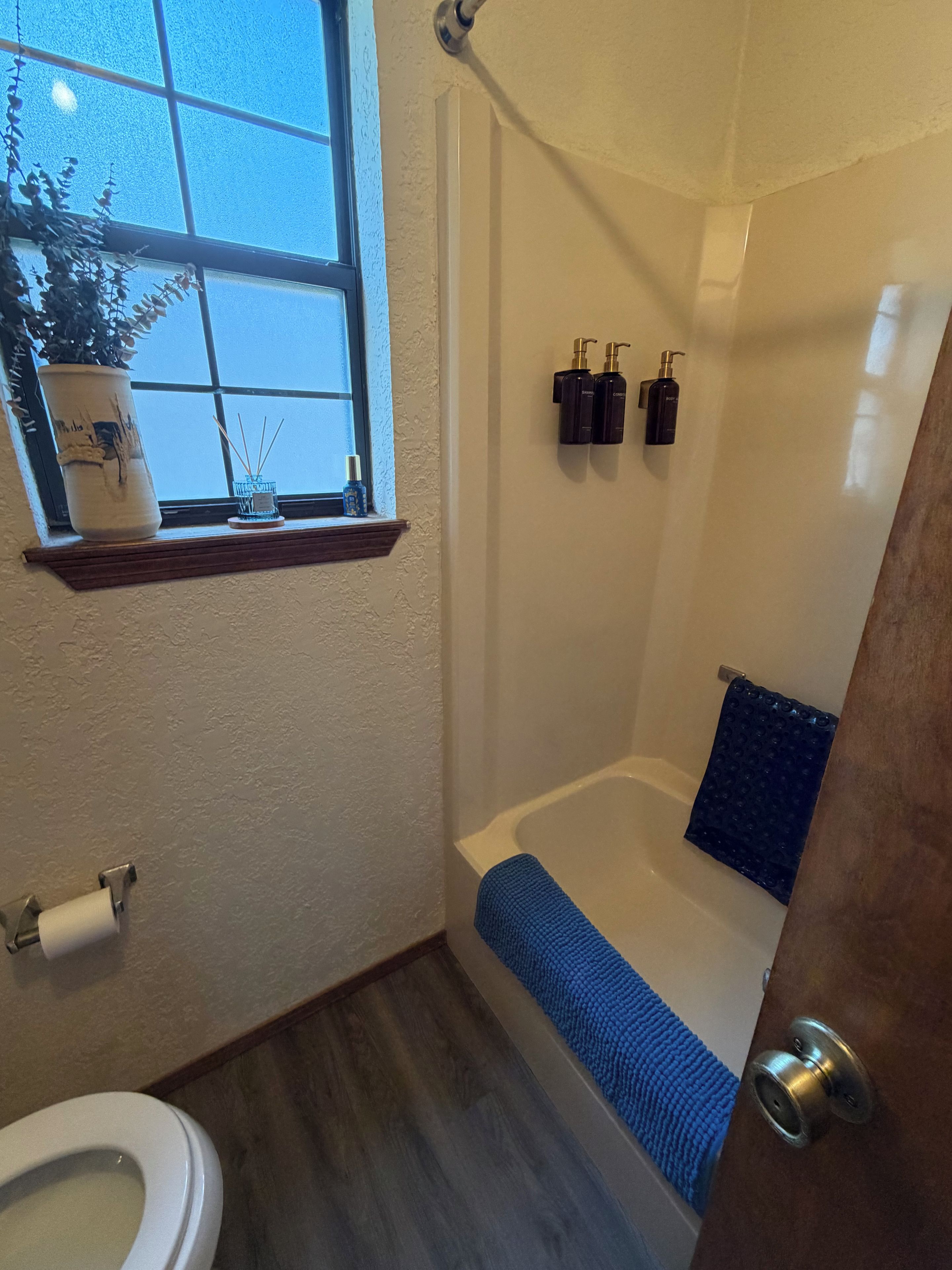 A bathroom with a bathtub, toilet, and window.