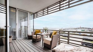 Ein Balkon mit Korbmöbeln, einem Tisch und Blick auf einen Yachthafen.