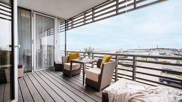 Ein Balkon mit Korbmöbeln, einem Tisch und Blick auf einen Yachthafen.