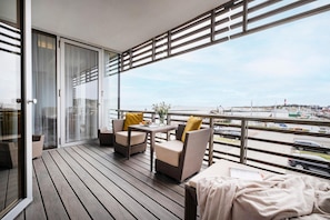 A balcony with wicker furniture, a table, and a view of a marina. - Budersand (Hörnum (Sylt))