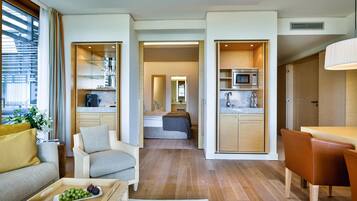 Ein modernes Interieur mit einer Couch, einem Esstisch, einer Küchenzeile und einem Schlafzimmer mit Bett und Spiegel.