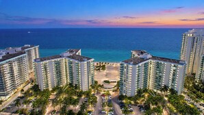 A high-rise hotel with multiple floors, a parking area, and a view of the ocean. - Oceanfront Luxury | 2BR Condo| No Resort Fees (Hollywood)