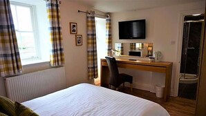 Una habitación de hotel con cama, escritorio, silla, televisor y baño.