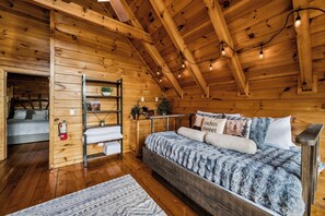 A wooden cabin interior with a loft bed, a shelf with plants, and a fire extinguisher. - Mountain Views, Four King Bedrooms, Hot Tub, Pool, Game Room &( EV Charger) (Pigeon Forge)