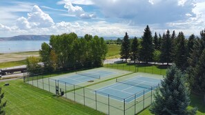 Ein Tennisplatz im Freien mit Blick auf einen See und Berge.
