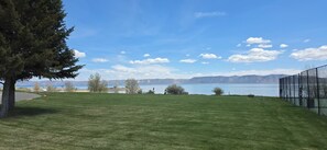 Ein grasbewachsenes Feld mit einem See und Bergen im Hintergrund.