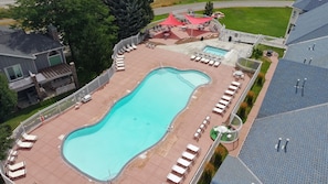 Eine Vogelperspektive auf ein Schwimmbecken mit Liegestühlen und einer überdachten Terrasse.