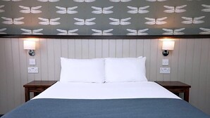 A hotel room with a bed, two bedside tables, and wall-mounted lamps. - Charnwood Arms by Good Night Inns (Coalville)