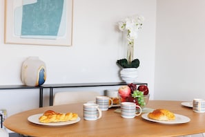 Una mesa de comedor con platos de comida, tazas a rayas y un jarrón con flores.